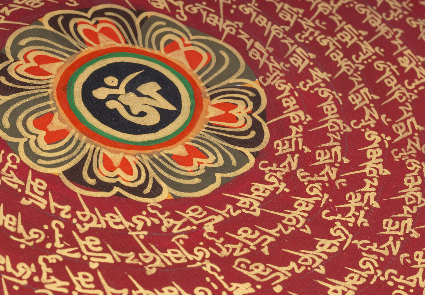 Handgemaltes Mantra-Mandala aus Nepal 30 x 30 cm auf handgemachter Canva Leinwand, blaue Umrandung um goldene Schrift auf rotem Hintergrund, Lotusblüte mit einem Om Zeichen im Zentrum