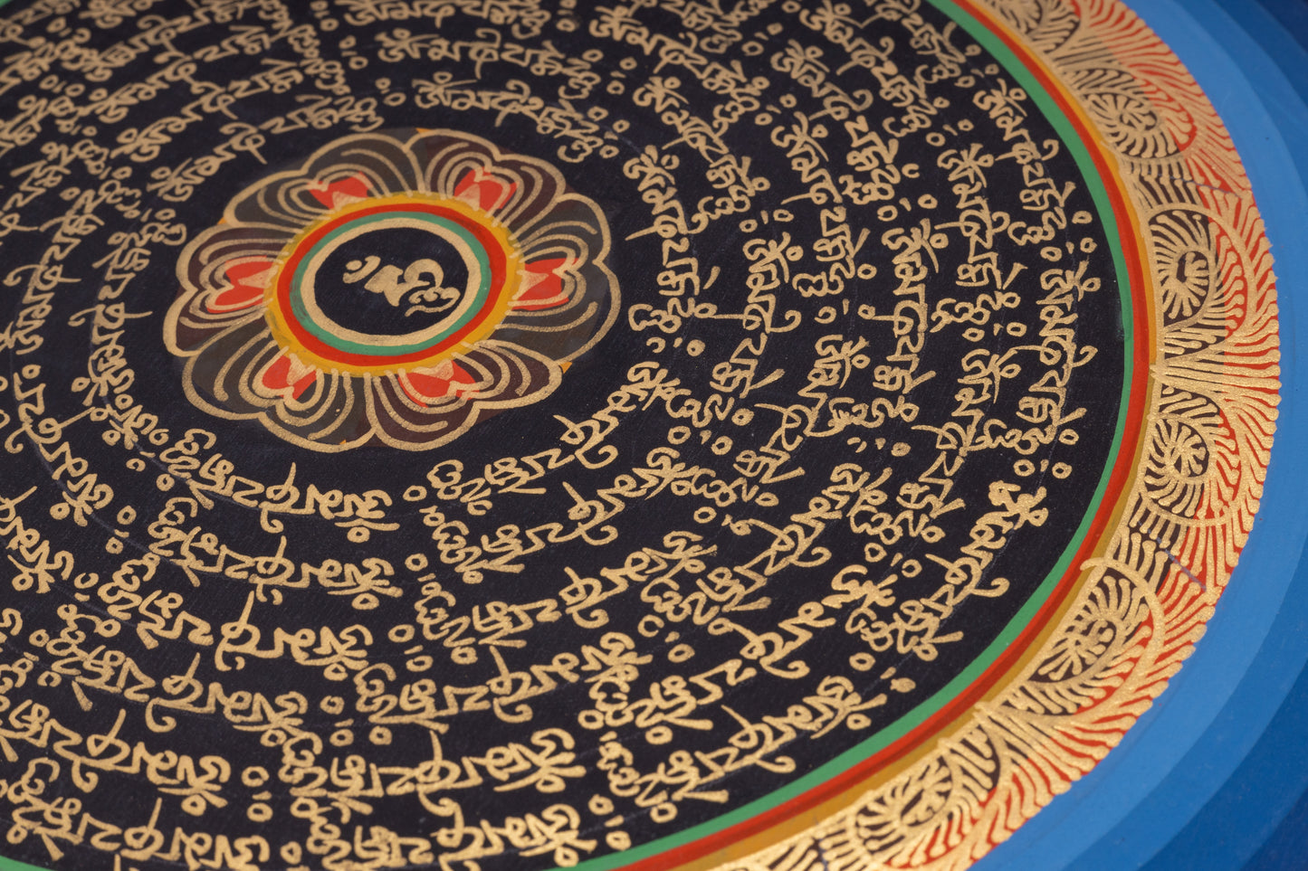 Handgemaltes Mantra-Mandala aus Nepal 30 x 30 cm auf handgemachter Canvas Leinwand, blaue und goldenen Umrandung um goldene Schrift auf schwarzem Hintergrund, Lotusblüte mit einem Om Zeichen im Zentrum